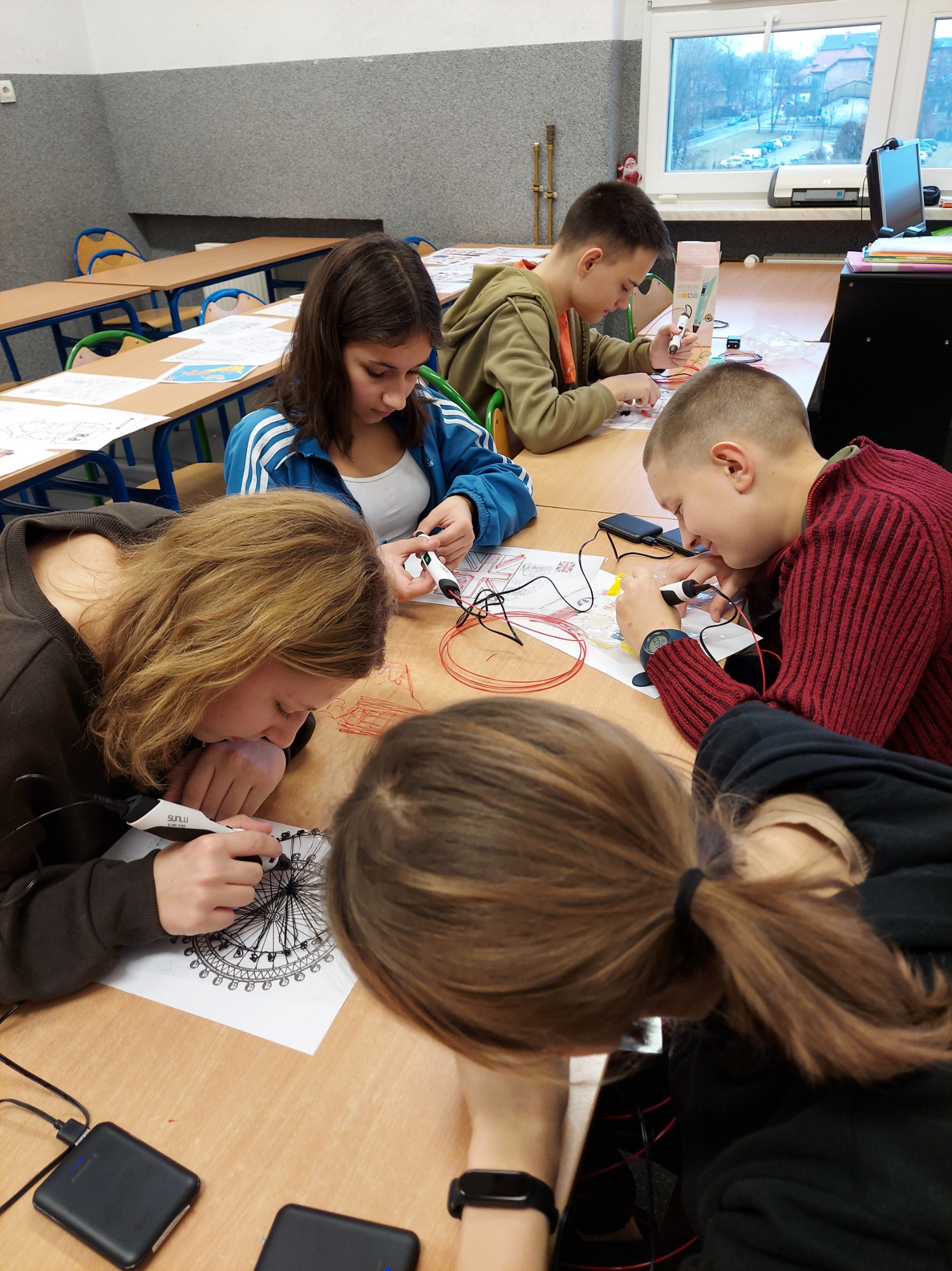 Uczniowie w klasie pracują używając długopisów 3D.
