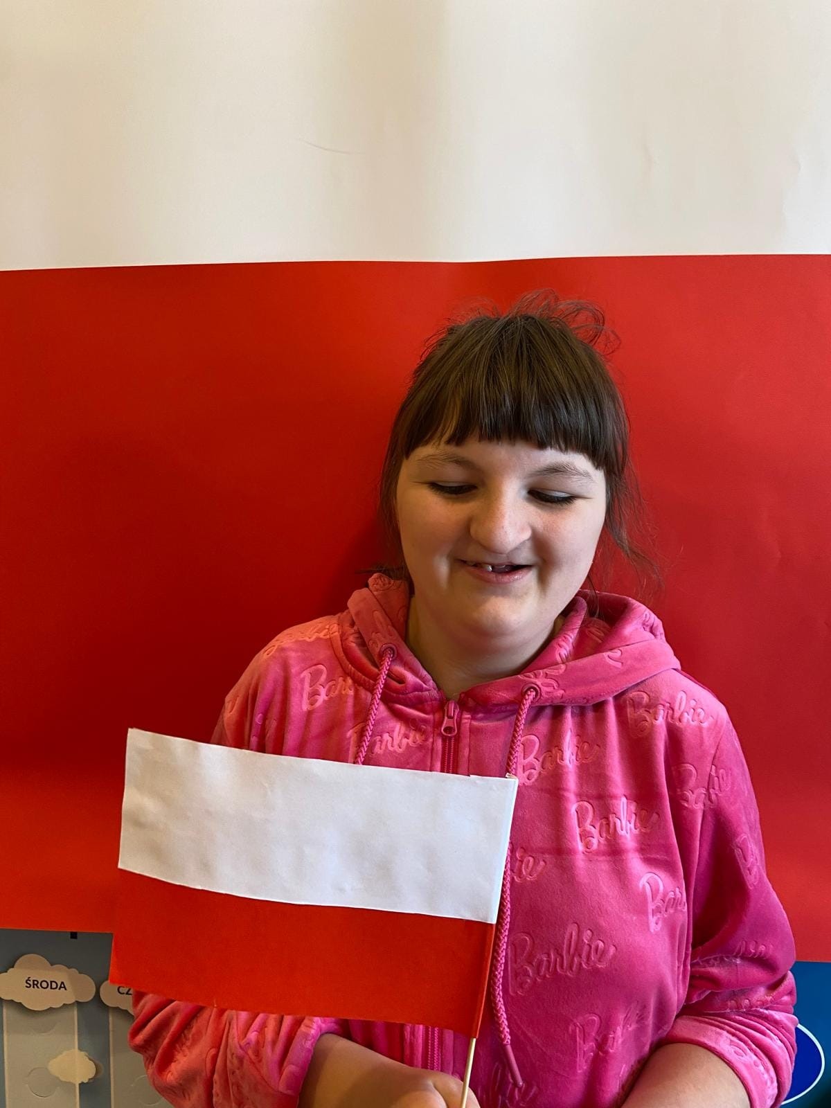 Uśmiechnięta uczennica trzyma w ręku flagę Polski