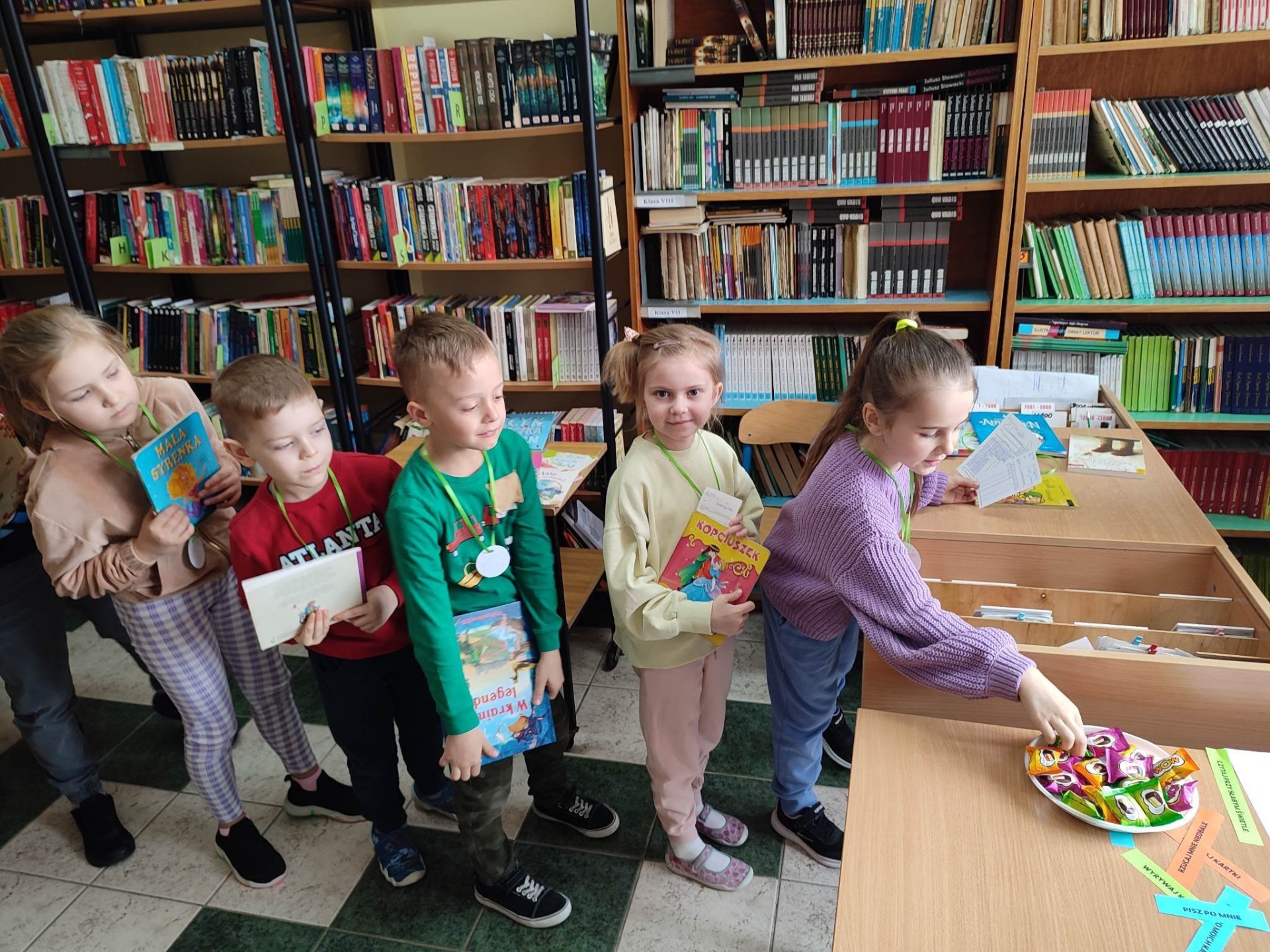 Uczniowie klasy 1 w trakcie wypożyczania książek.