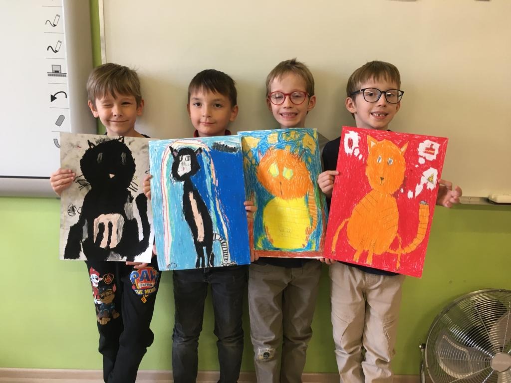 Dzieci klasy 1a pozujące własnoręcznie narysowane koty.