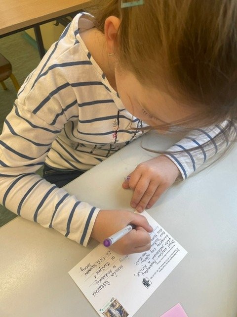 Dziewczynka podpisuje kartkę pocztową 
