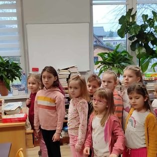 Grupa dzieci zwiedza bibliotekę szkolną.