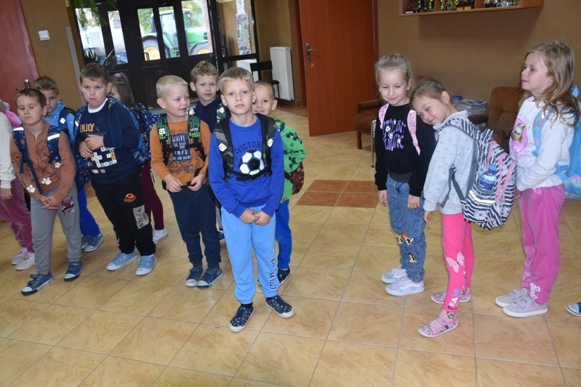 Grupa uczniów z plecakami na  szkolnym korytarzu