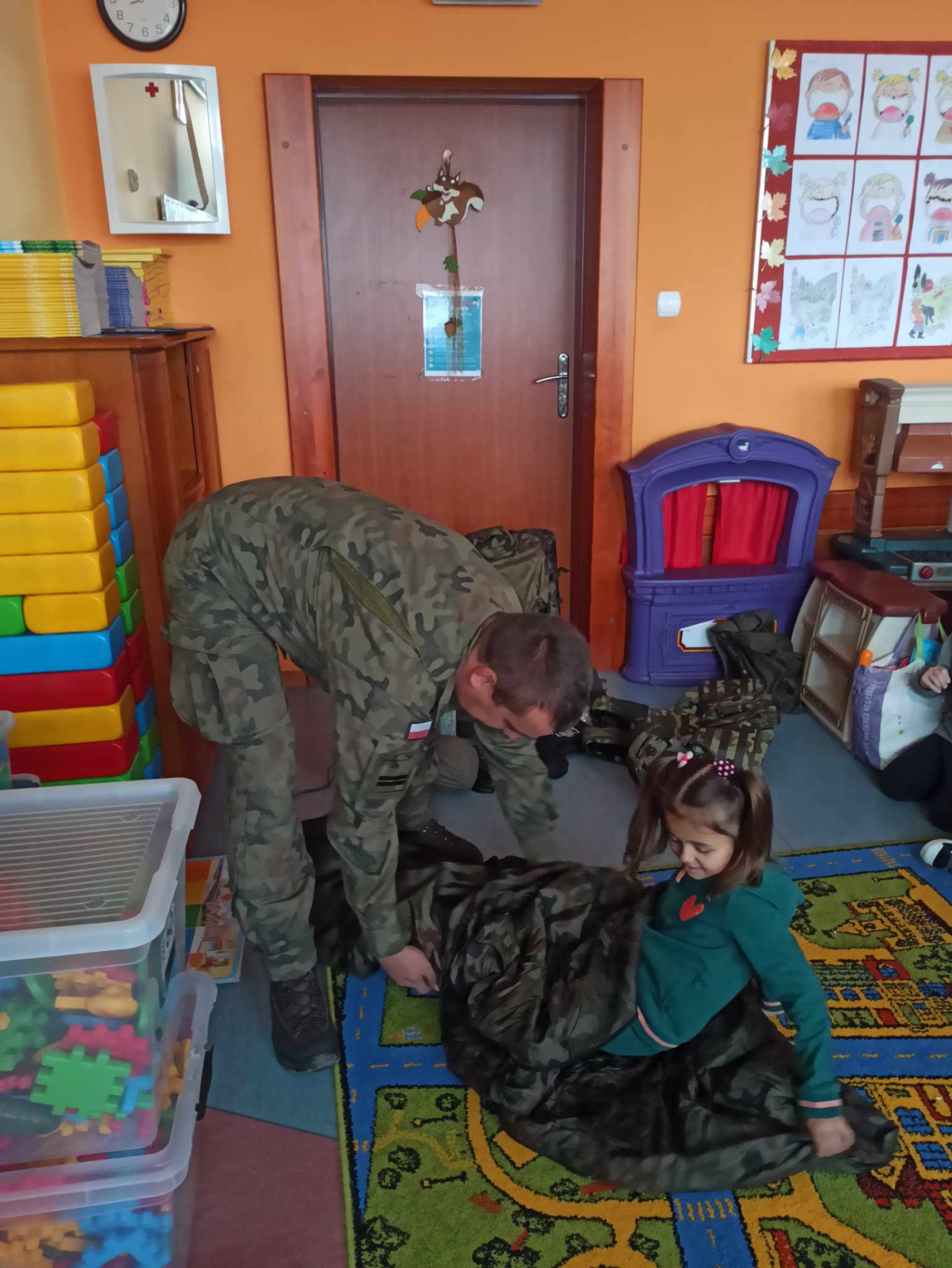 Żołnierz pokazuje sposób korzystania ze śpiworu wojskowego.