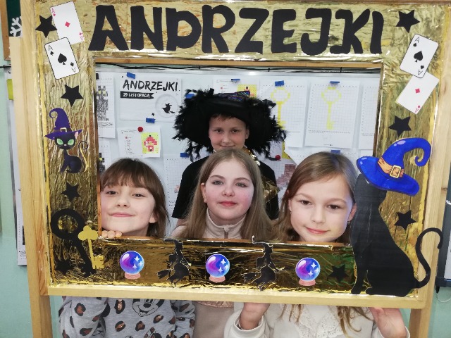 Twarze 3 uczennic i 1 ucznia w kapeluszu  w ramce z napisem "Andrzejki".
