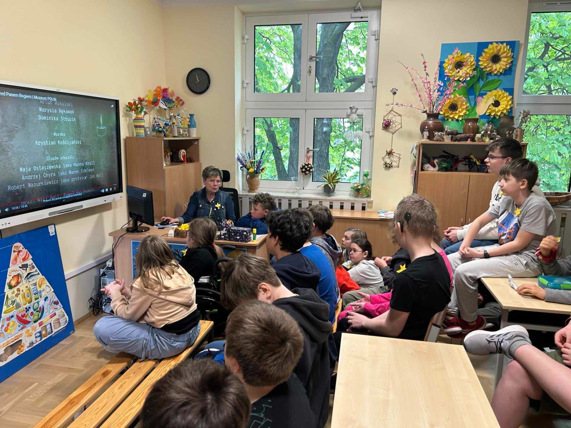 Uczniowie oglądający wiadomości na tablicy interaktywnej. 
