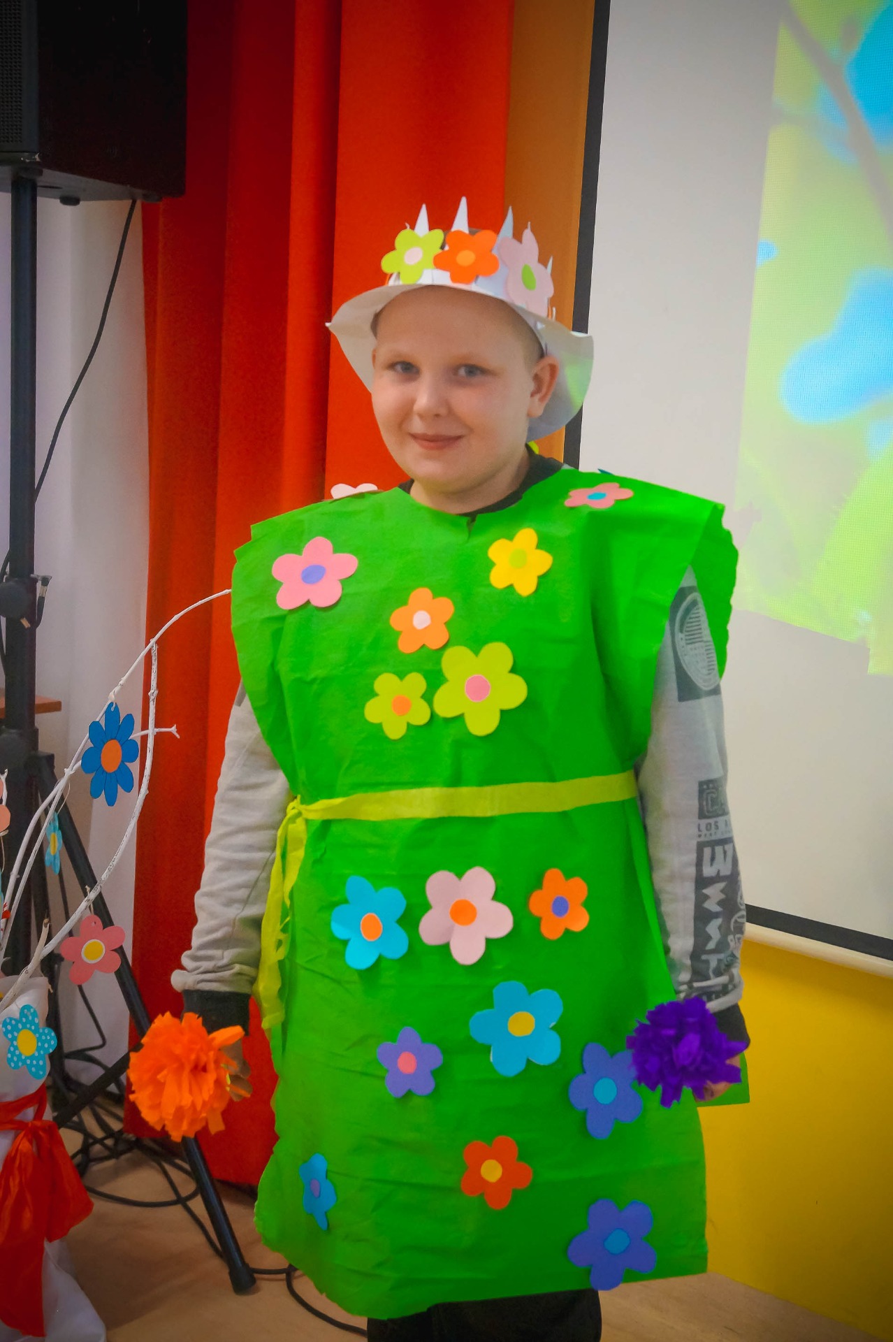 Chłopiec przebrany za Pana Wiosnę, ma ubranie robione z zielonej bibuły, na niej kwiaty