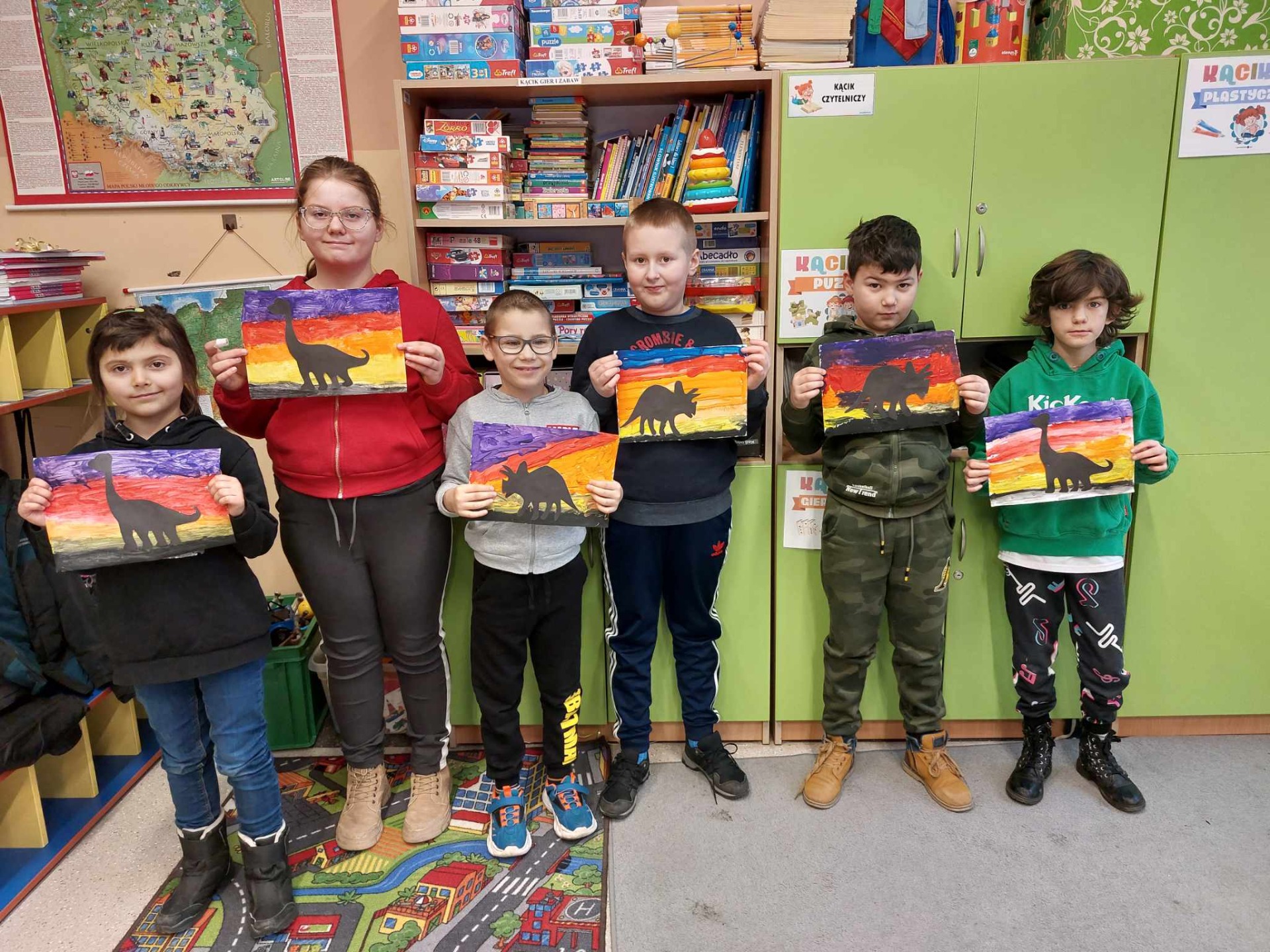 Uczniowie prezentują prace malowane wcześniej farbami